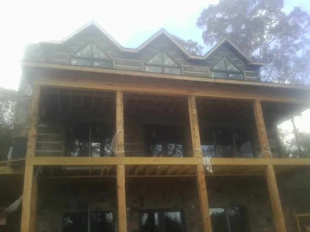Dormers and porch framing on a large log home under construction — Roof Coating work by our crew in Royalton