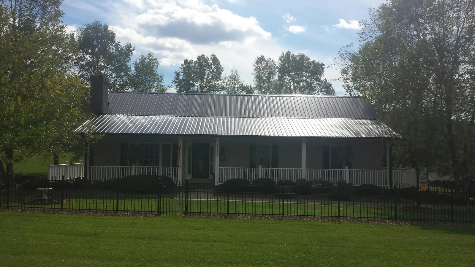Gray metal roof on a brick ranch with a full width front porch — Gutter Guard Installation work by our crew in Royalton