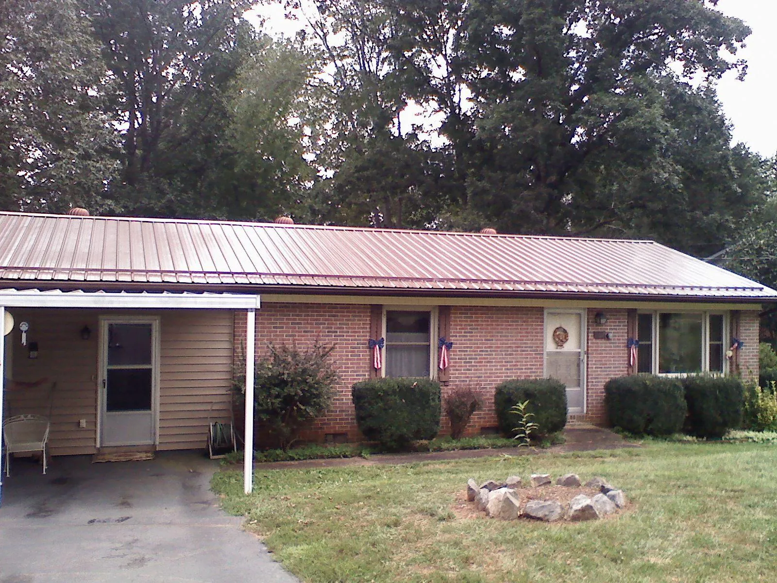 Bronze metal roof and carport on a brick ranch home — Roof Repair work by our crew in Royalton