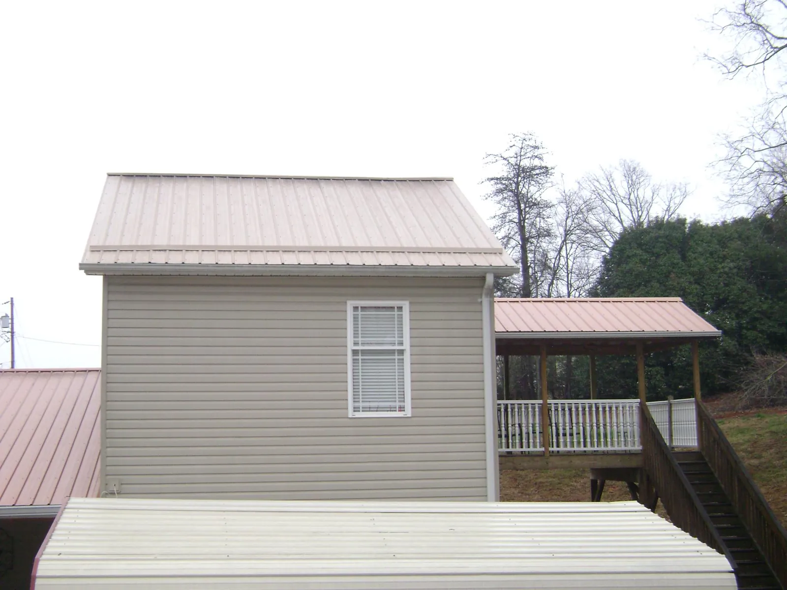 Tan metal roofs on a two story addition and attached porch, from a Roof Replacement job in Royalton