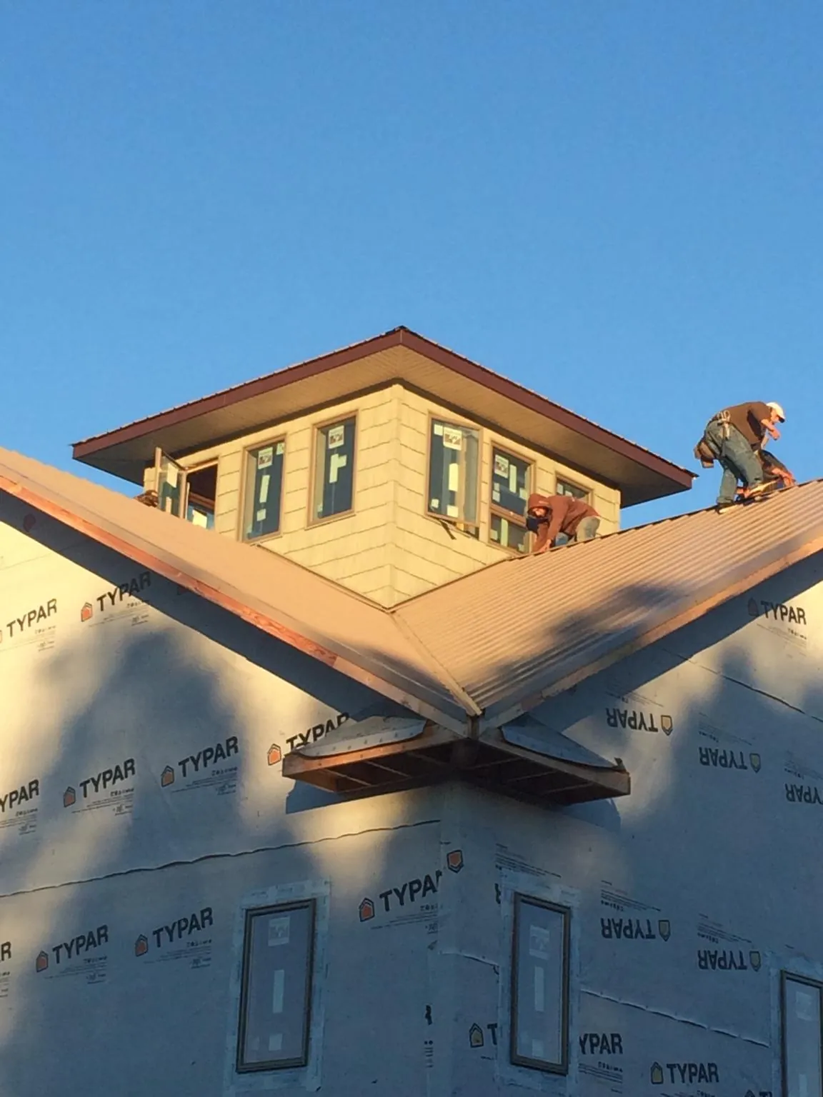 Roofers working around a rooftop cupola on a new metal roof at sunset — Roof Waterproofing in Royalton by Roofing Brothers